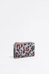 Monedero pequeño con estampado animal print en tonos lila, negro y naranja. Tiene cierre con cremallera dorada y logo de la marca en el frente. Interior con tarjetero y forro con logo grabado.