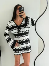 Vestido corto tejido a crochet, con escote en V y mangas largas acampanadas. Diseño a rayas horizontales en blanco y negro.