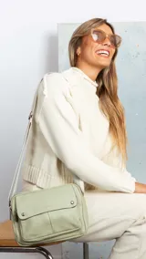 Bandolera de símil cuero color verde menta, con apertura central de cierre, bolsillo principal con cierre metálico y bolsillo frontal con tapa y broches magnéticos. Incluye bolsillos internos y posterior, y correa de galón combinada larga y regulable.