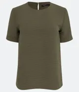 Blusa blanca de poliéster con cuello redondo, mangas cortas, cierre trasero en forma de gota, pequeñas aberturas laterales y acabados en pespuntes en las mangas y el cuello.