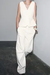 Pantalón de tiro medio confeccionado en hilatura de algodón color blanco. Cuenta con trabillas en la cintura, bolsillos laterales ocultos en costura y cierre frontal con cremallera, botón y ganchos metálicos.