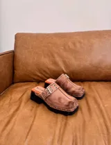 Zueco negro liviano con suela de goma y detalles metálicos, de diseño moderno.