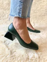 Zapato de cuero verde oscuro con punta cuadrada y tacón geométrico negro. Forro, capellada y plantilla 100% cuero. Tacón de 5 cm.