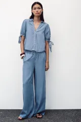 Pantalón celeste de tiro alto con cintura elástica ajustable con cordones, bolsillos delanteros y traseros, y pernera ancha.