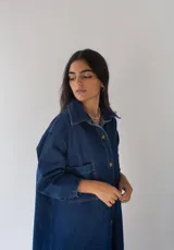 Vestido camisero largo de denim azul con botones frontales, cuello camisero, mangas largas y bolsillos de parche en el pecho.