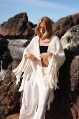 Triángulo de lana tejido a mano, color crudo, con flecos largos en todo el borde.