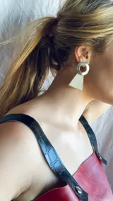 Aros colgantes con forma geométrica, hechos con guampa y detalles metálicos dorados o plateados.
