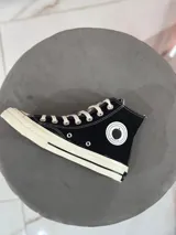 Zapatillas de lona blancas de caña alta con cordones y puntera de goma. Logo de durazno engomado en la base y en la cara interna.