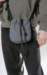 Bolso gris tipo drawstring con correa larga negra con logo de la marca en blanco.