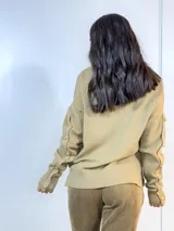 Sweater color camel de tejido de punto con cuello redondo y mangas largas. Presenta detalle de botones dorados en los puños y en los hombros.