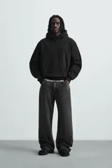Sudadera con capucha color crudo, de corte relajado, confeccionada en tejido de algodón con interior rizado. Cuenta con cuello con capucha, manga larga, bolsillo frontal tipo canguro y acabados en rib.