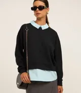 Buzo negro de algodón con cuello de camisa celeste con detalles de strass.
