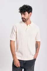 Sweater de tejido de punto color crudo, manga corta, con cuello polo y escote en V. Presenta un diseño acanalado vertical.