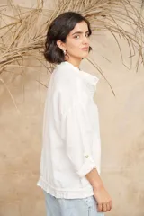 Camisa blanca de lino con cuello mao, mangas 3/4 con botón para sujetar, cierre con botones a tono y ajuste con cordón en la cintura.