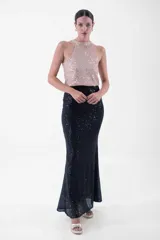 Vestido largo de fiesta con cuello halter y lentejuelas color verde esmeralda en el top y negro en la falda.