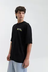 Remera color café de corte oversize con cuello redondo y mangas cortas. Estampado en la espalda con la frase "Stay Original Forever" y varios diseños gráficos.