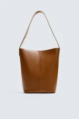 Bolso tipo shopper color marrón, fabricado en piel. Tiene un compartimento principal con cierre de imán y un bolsillo plano interior. El asa de hombro también es de piel.