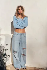 Top celeste de punto con cuello redondo amplio y manga larga. Detalle de frunces delanteros y botones en hombros forrados a tono.
