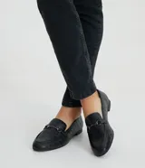 Mocasines negros con textura croco, puntera redondeada y detalle metálico en la parte superior.