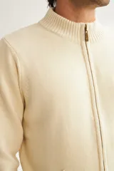 Campera de lana color crema, tejida con cierre delantero, cuello alto y bolsillos delanteros.