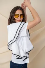 Blusa blanca de algodón con volado en un costado y vivo negro.