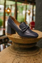 Zapato clásico de cuero azul marino, con aplique decorativo en el empeine y taco cuadrado.