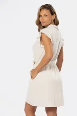 Vestido corto color beige de lino, con cuello camisero, mangas cortas con volados, cierre frontal con botones y lazo para ajustar en la cintura.