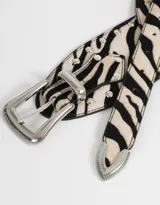 Cinturón con estampado de cebra, apliques de tachas plateadas y hebilla metálica plateada.