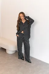 Camisa negra con estampado de lunares blancos, de manga larga y cuello clásico.