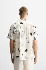 Camisa de manga corta con cuello bowling y estampado floral en tonos blanco y negro.