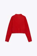 Jersey rojo de punto con cuello redondo y manga larga. Bajo con aberturas laterales.