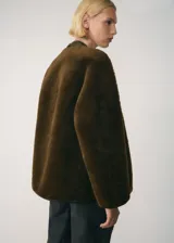 Chaqueta de tejido efecto borreguito en color marrón, con forro interior y cierre de botones de trenca.