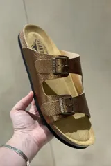 Sandalias blancas de cuero con doble tira y hebillas metálicas ajustables. Suela anatómica de corcho y goma.