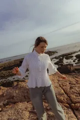 Camisa blanca de poplin de algodón con alforzas verticales y cuello alto estructurado. Mangas 3/4 con detalle de pliegues.