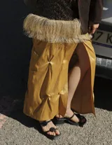 Sandalias negras de plataforma baja con dos tiras finas adornadas con rosetas negras. Una tira cruza sobre los dedos y la otra funciona como pulsera tobillera.