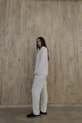 Pantalón verde con finas rayas verticales blancas, corte recto, tiro alto y bolsillos laterales.