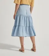 Pollera midi de liocel celeste, con corte evasé y tres niveles de volantes. Presenta abotonadura frontal completa y ruedo desflecado.