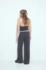 Pantalón de tiro bajo, calce relajado y pierna amplia, color marrón oscuro con textura acanalada. Presenta cintura ajustable con lazo.