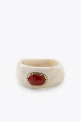 Pack de dos pulseras rígidas, una dorada de metal y otra de resina color crema con veta marrón y aplique de piedra ovalada color coral con engarce dorado.