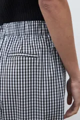 Pantalón de tiro alto, corte ancho y holgado, con elástico en la cintura. Confeccionado en tela estampada a cuadros vichy en blanco y negro.