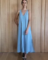 Vestido largo de jean celeste, corte recto, con breteles finos y escote en V. Presenta aberturas laterales en el ruedo.