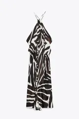 Vestido largo de viscosa con estampado animal en blanco y negro. Tiene cuello halter ajustable con lazos y bajo asimétrico.