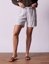 Short blanco con rayas verticales grises, de lino y rayón. Tiene pretina ancha elastizada con lazo de ajuste y bolsillos delanteros.