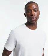 Remera blanca de corte regular, confeccionada en media malla con textura diferenciada. Tiene cuello redondo y mangas cortas.