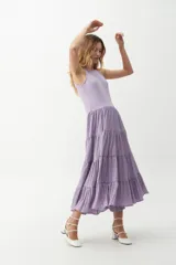 Vestido midi color lila, con cuerpo superior ajustado de punto canalé y falda amplia de tres niveles con textura arrugada.