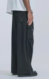 Pantalón cargo negro de corte ancho, con cintura elástica, cinturón con hebilla y múltiples bolsillos.