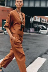 Pantalón color ladrillo de tiro alto con pinzas delanteras, cintura elástica en la espalda, bolsillos delanteros y traseros. Cierre frontal con cremallera y botón.