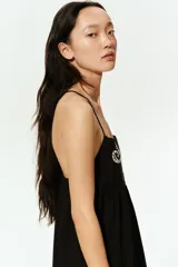 Vestido corto negro de algodón con breteles finos cruzados en la espalda, escote cuadrado, bordado floral en el busto y volados en el ruedo.