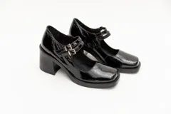 Guillermina de cuero negro con punta cuadrada, taco bloque y correa sobre el empeine con hebilla dorada.