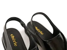 Sandalias negras de charol con tiras cruzadas, talón con elástico interno y plantilla de cuero acolchada. Plataforma media.